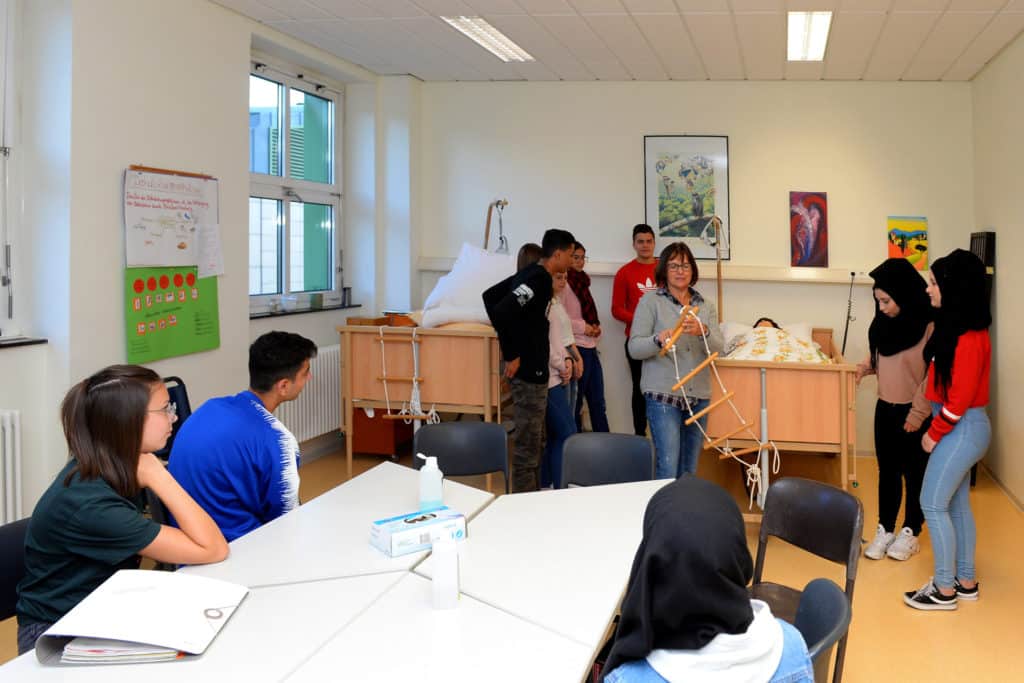Das Bild zeigt eine Gruppe von Lernenden und eine Lehrkraft beim praktischen Teil des Schulunterricht.